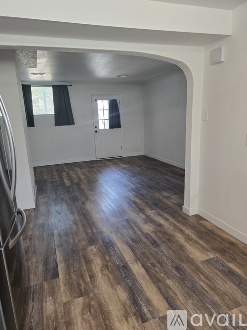A kitchen with a refrigerator and a wooden floor.