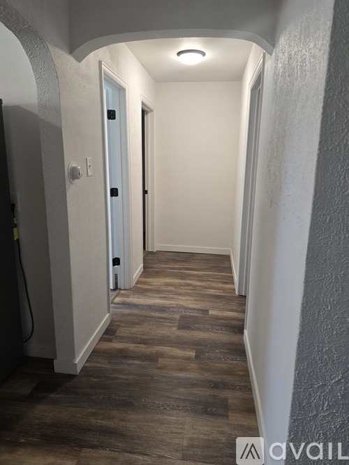 A hallway with a wooden floor and white walls.