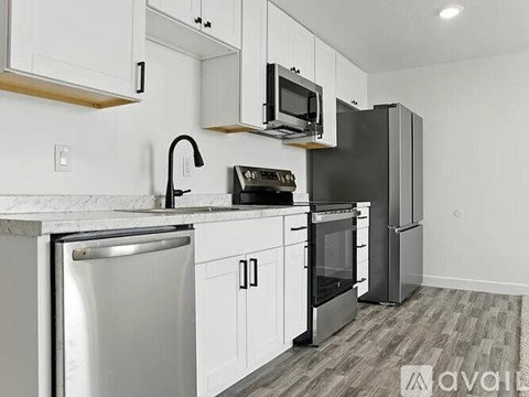 A kitchen with a refrigerator, microwave, oven, and sink.
