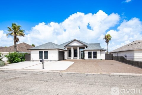 A house with a driveway and palm trees in front.