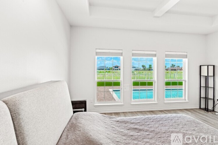 A bedroom with a large bed and a view of a pool through the windows.