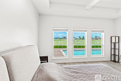A bedroom with a large bed and a view of a pool through the windows.