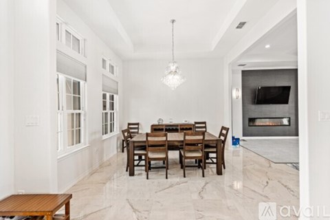 A dining room with a table set for six and a fireplace in the background.