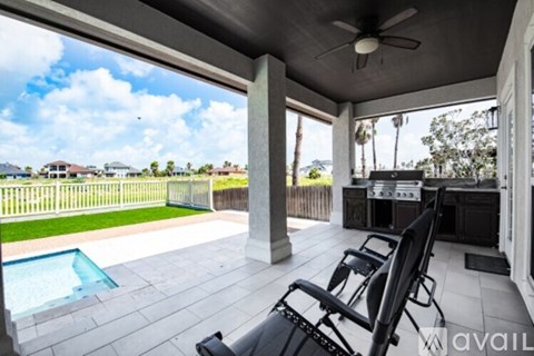 A sunny day at the poolside with a chair and a ceiling fan.