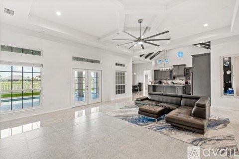 A spacious living room with a large sofa set and a kitchen area in the background.
