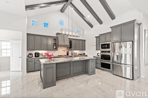 A modern kitchen with dark grey cabinets and stainless steel appliances.