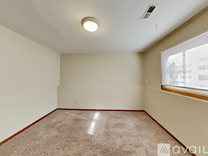 A room with a carpeted floor and a window with blinds.