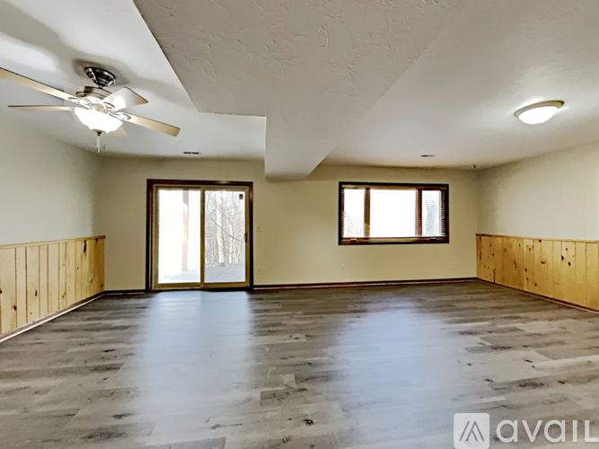 A spacious room with wooden floors and a ceiling fan.