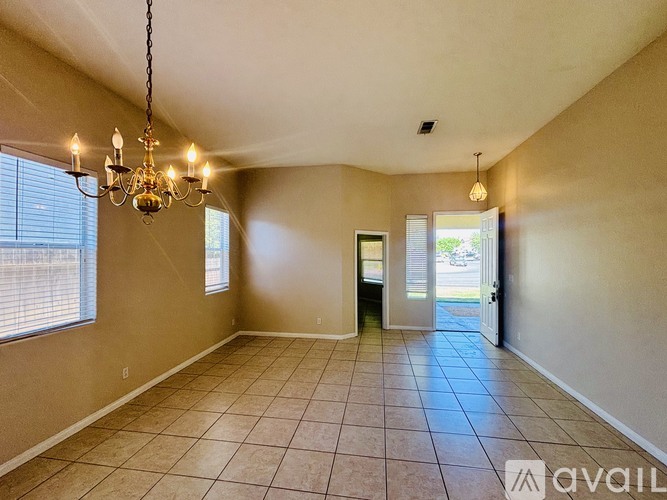 A room with beige walls, a chandelier, and a tiled floor.