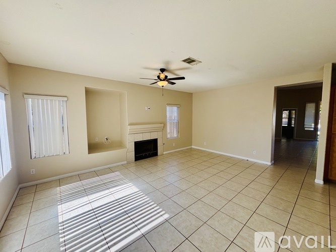 A spacious living room with a fireplace and a ceiling fan.