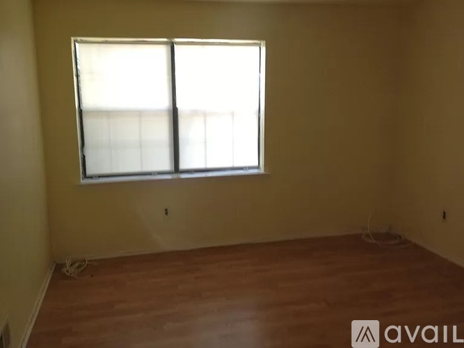A room with a large window and wooden flooring.