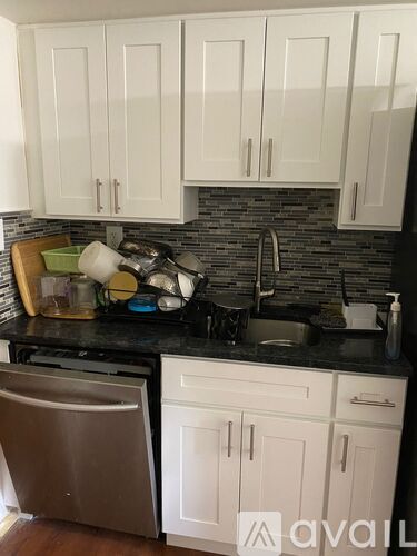 A kitchen with white cabinets and a black countertop.