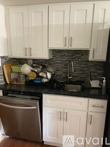 A kitchen with white cabinets and a black countertop.