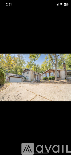 A house with a driveway and trees in the background.