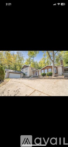 A house with a driveway and trees in the background.