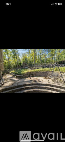 A playground with swings and a slide in a wooded area.