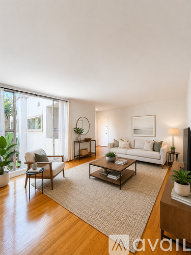 A living room with a white couch, a coffee table, and a large window.