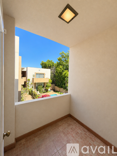 A room with a tiled floor and a door leading to a balcony with a view of a pool and trees.