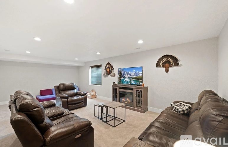A living room with brown leather furniture and a flat screen TV mounted on the wall.
