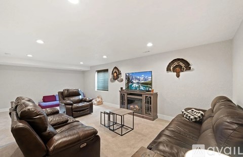 A living room with brown leather furniture and a flat screen TV mounted on the wall.