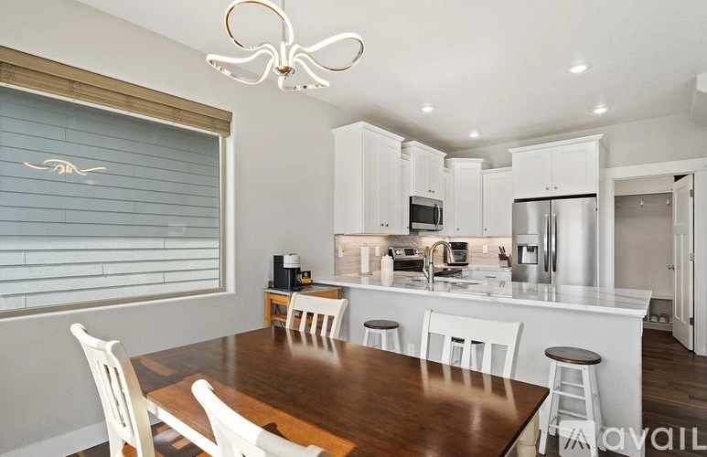 A modern kitchen with white cabinets and a wooden dining table.