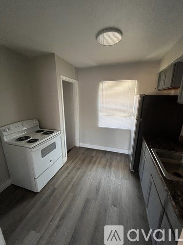 A kitchen with a stove, sink, and cabinets.