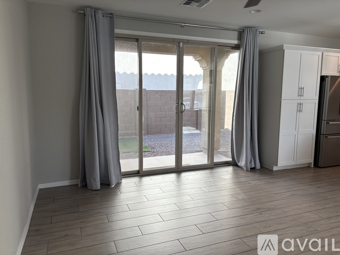 A room with a sliding glass door and grey curtains.