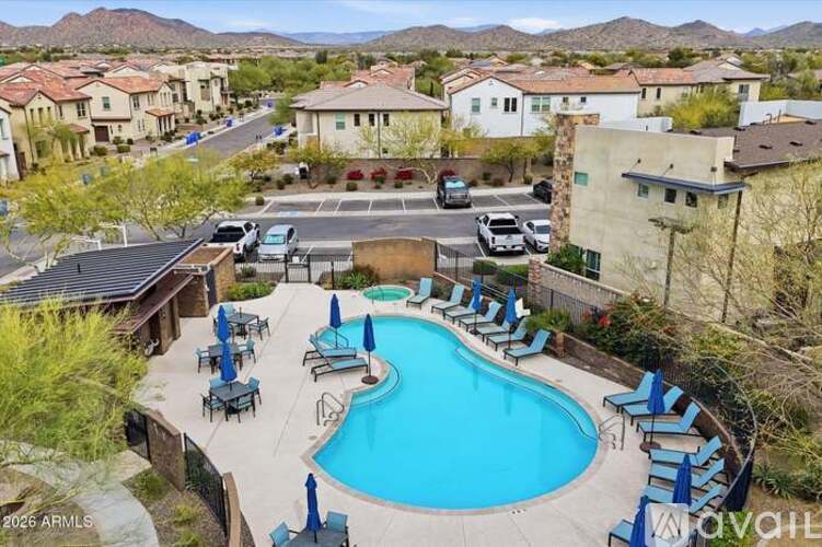 A pool surrounded by lounge chairs and umbrellas in a residential area.