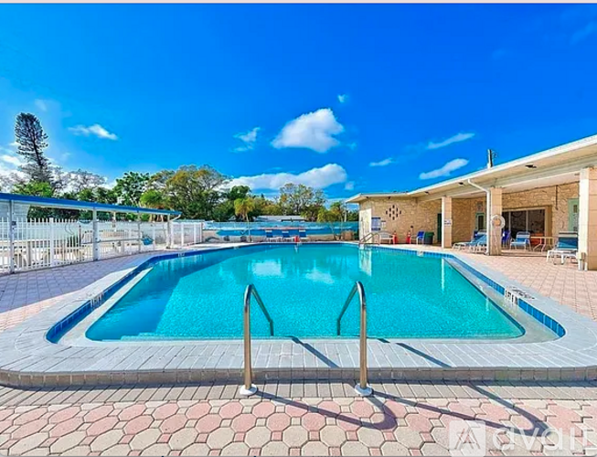 A large outdoor swimming pool with a blue sky and clouds in the background.