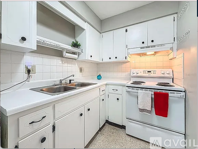 A white kitchen with a stove, sink, and cabinets.