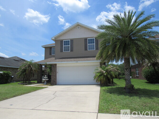 A house with a garage and a palm tree in front.