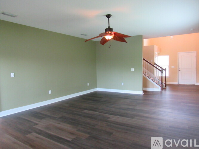 A room with a ceiling fan and wooden flooring.