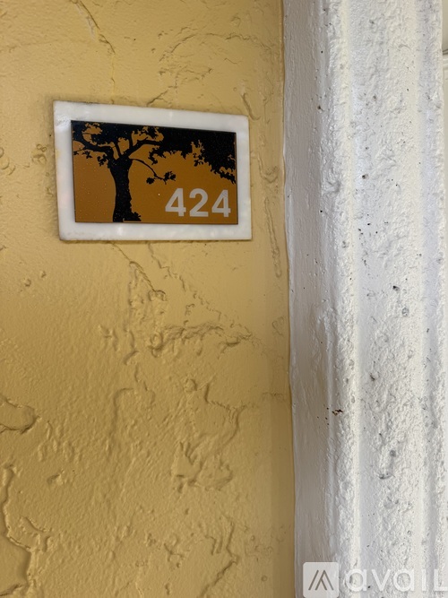 A white door with a plaque that has a tree and the number 424 on it.