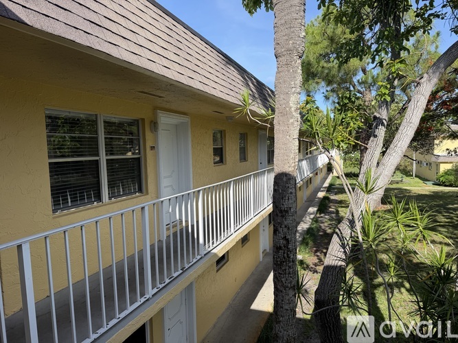 A balcony with a metal railing and a tree in front of a house.