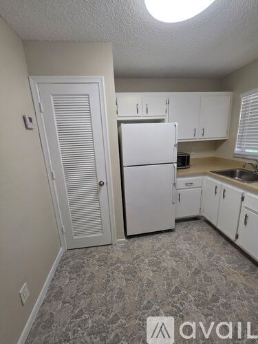 A kitchen with a white refrigerator and cabinets.