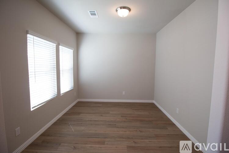 A room with wooden flooring and a window with blinds.