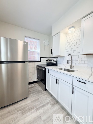 A kitchen with a stainless steel refrigerator and white cabinets.