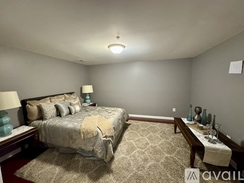 A bedroom with a large bed and a nightstand with a lamp.