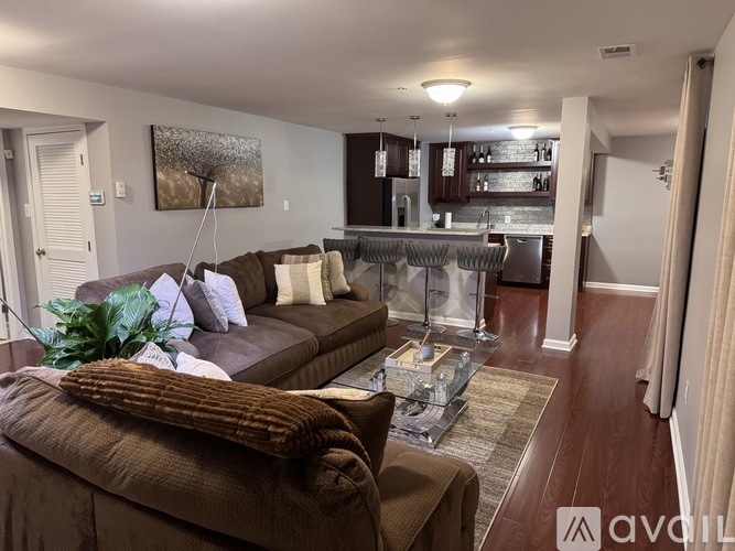 A living room with a brown couch and a glass coffee table.