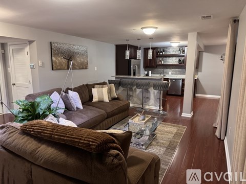 A living room with a brown couch and a glass coffee table.