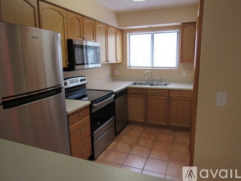 A kitchen with wooden cabinets and a stainless steel refrigerator.