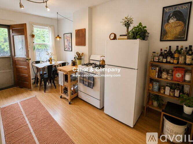 A kitchen with a white fridge and a dining table with chairs.