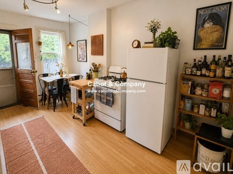 A kitchen with a white fridge and a dining table with chairs.