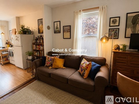A living room with a couch, a refrigerator, and a window.