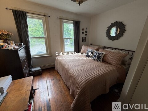 A bedroom with a bed, a desk, and a window with a view of the backyard.