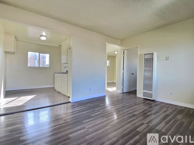 A spacious room with wooden flooring and white walls.