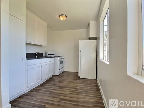 A kitchen with white cabinets and a wooden floor.