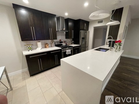 A modern kitchen with dark brown cabinets and a white island.