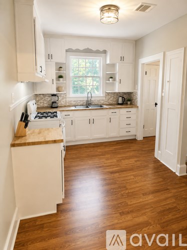 A kitchen with white cabinets and a wooden floor.