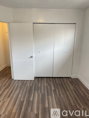 A room with a white closet and wooden flooring.